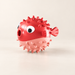 Red and pale pink pufferfish dog toy on ivory surface
