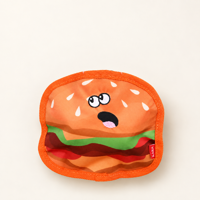 Orange hamburger-shaped fabric dog toy on ivory surface