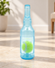 Translucent blue bottle-shaped dog toy with a green ball inside, standing on a pale stone floor.