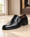 Black slip-on dress shoe with an apron seam, a small metal emblem and a low heel in a dressing room.