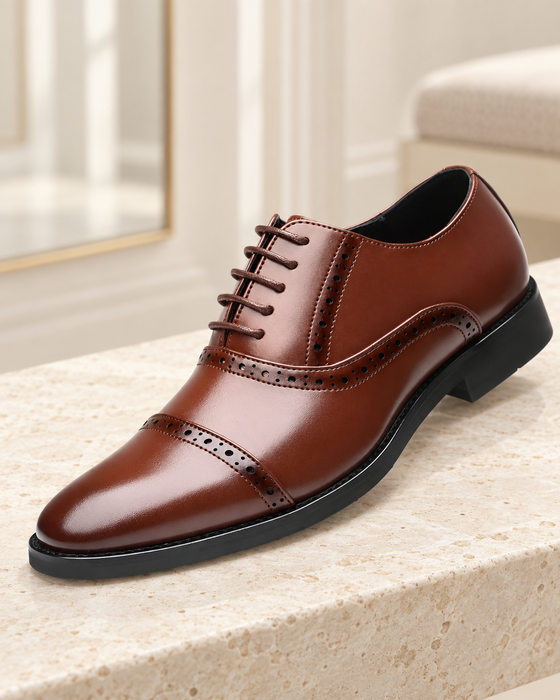 Brown Oxford dress shoe with perforated seams and five lace passes on a pale stone bench.