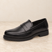 Black perforated loafer on an ivory stone surface