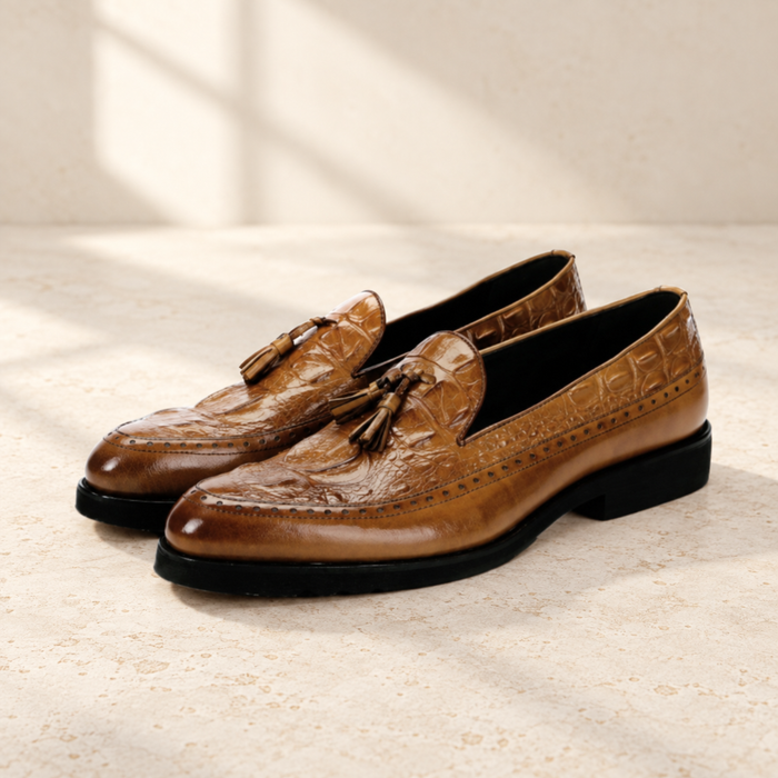 Brown embossed tassel dress shoes on an ivory stone surface