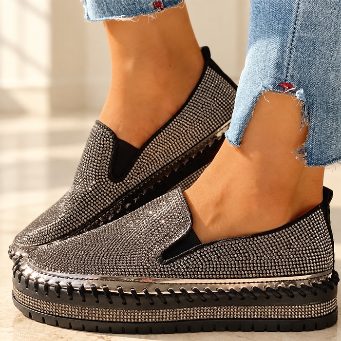 Black rhinestone slip-on shoes with stitched soles worn with cropped jeans