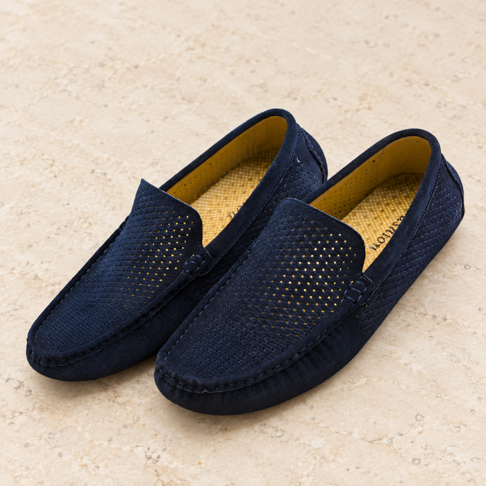 Navy perforated loafer pair with yellow lining on ivory stone