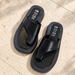 Black asymmetrical sandals on an ivory stone terrace.