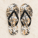 Animal-pattern flip-flops with black straps on pale stone.