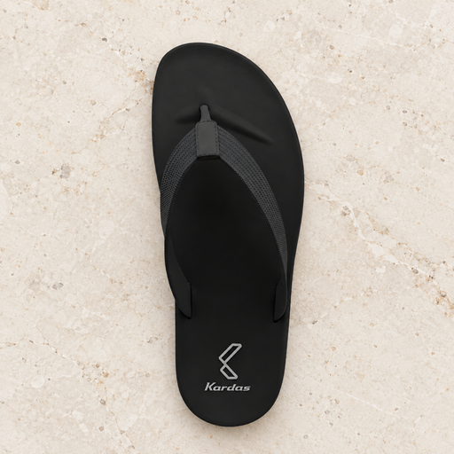 Black flip-flop with its original silver heel mark on ivory stone.
