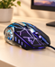Black gaming mouse with blue and purple lighting on an ivory desk.