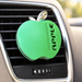 Green apple-shaped fragrance mounted on a car air vent.