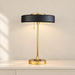 Black and gold table lamp with pull chain on an ivory sideboard.