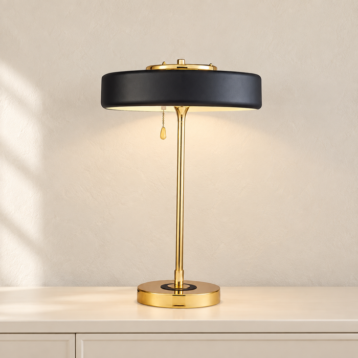 Black and gold table lamp with pull chain on an ivory sideboard.