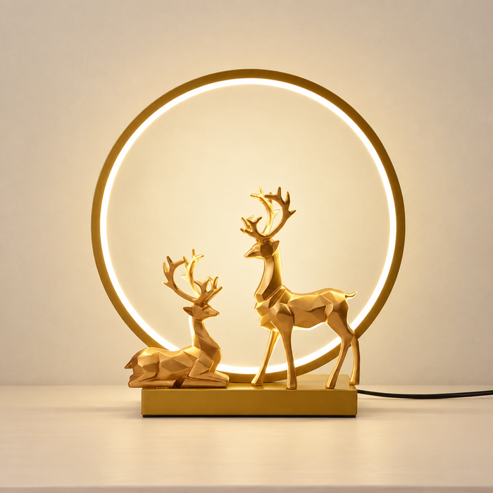 Golden ring lamp with two faceted deer on an ivory sideboard.