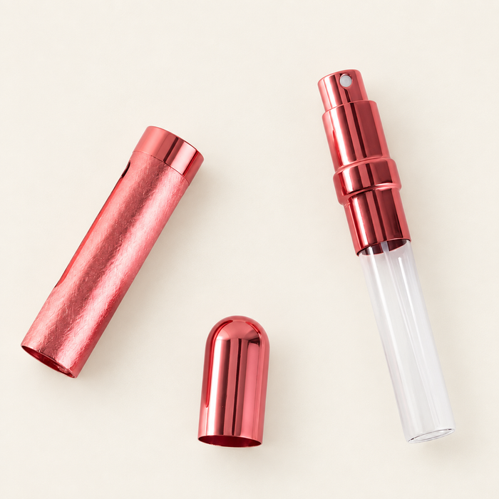 Three components of a rose-coloured perfume atomizer