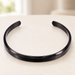 Black open cuff bracelet on an ivory surface.