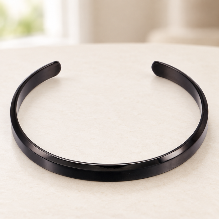 Black open cuff bracelet on an ivory surface.
