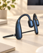 Dark open-ear headphones with a microphone boom on an ivory desk.
