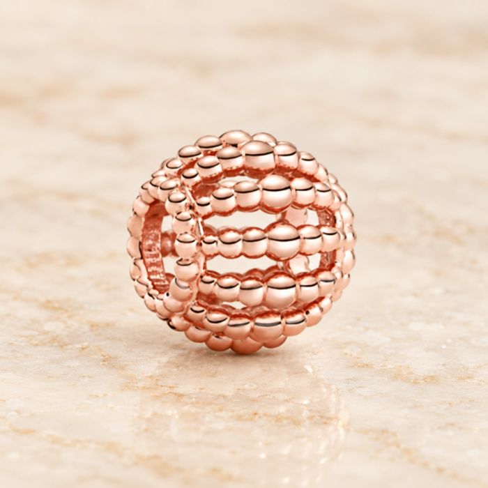 Rose-gold openwork bead resting on ivory stone