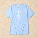 Pale blue short-sleeve T-shirt with a white bicycle graphic, laid flat on stone.