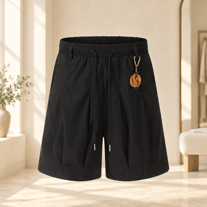 Black drawstring shorts with an orange and gold pendant in an ivory dressing room