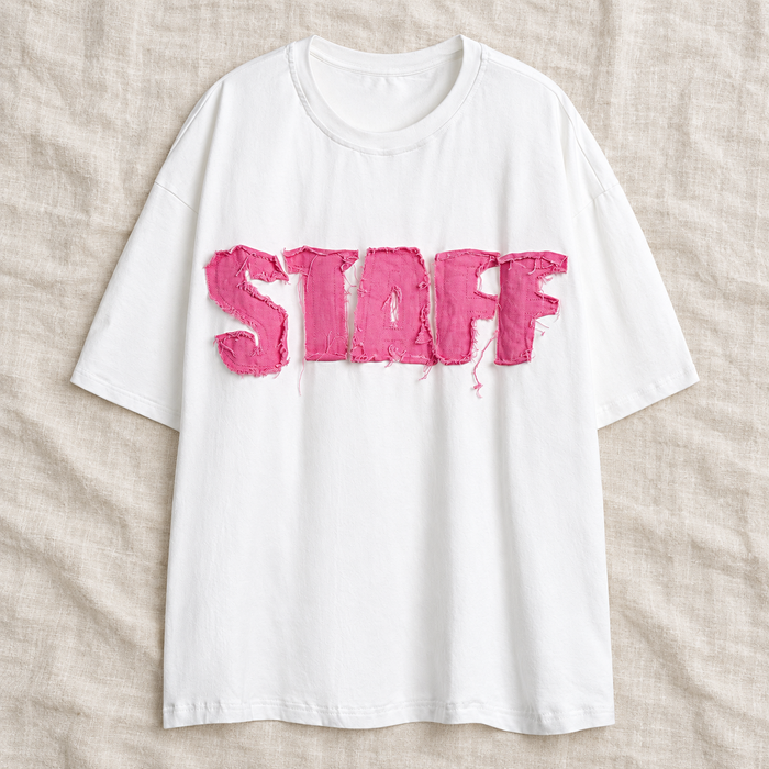 White short-sleeve T-shirt with pink raw-edge STAFF applique laid on ivory linen