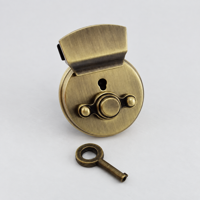 Brushed bronze bag lock and matching key on an ivory surface