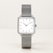 Silver square analogue watch with white dial and mesh bracelet on an ivory surface