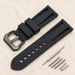 Black rubber watch strap with buckle and fitting components on ivory stone.