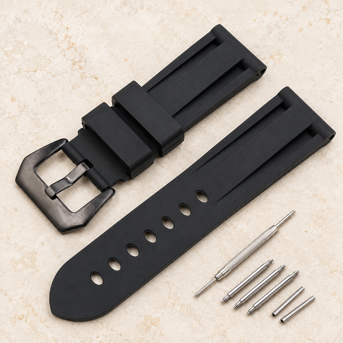 Black rubber watch strap with buckle and fitting components on ivory stone.