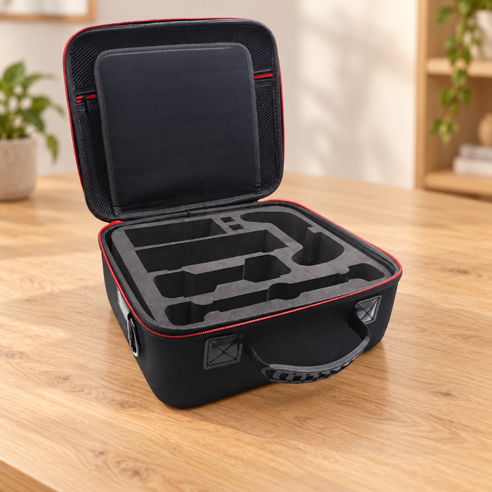 Open black console storage case with empty fitted foam compartments and red zipper trim on a wooden table.
