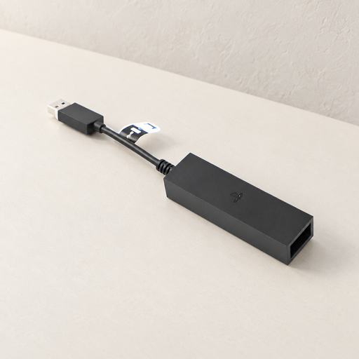 Black camera adapter with short USB cable on an ivory surface