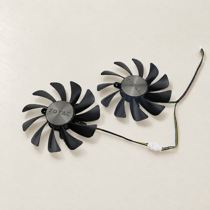 Pair of black cooling fans with ZOTAC hubs and connecting wires on ivory surface