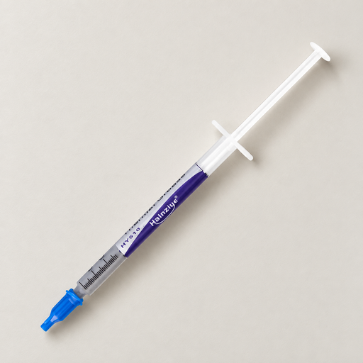 Thermal paste syringe with a blue cap on an ivory work surface