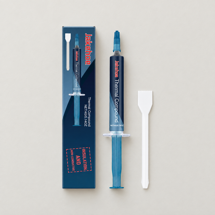 Blue thermal compound syringe with spatula and carton on ivory surface