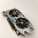 Black dual-fan graphics card with gold contacts on an ivory surface.