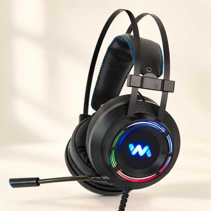 Black gaming headset with RGB earcup lighting, blue headband stitching and boom microphone on an ivory surface