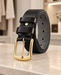 Rolled black leather belt with a gold buckle and two keeper loops on a pale stone dressing table.