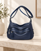 Navy blue shoulder handbag with curved front pockets, silver-tone zipper pulls and an adjustable strap.