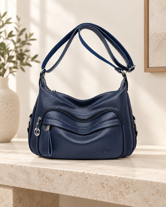 Navy blue shoulder handbag with curved front pockets, silver-tone zipper pulls and an adjustable strap.