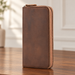 Long brown zip-around wallet standing on a walnut dressing table.
