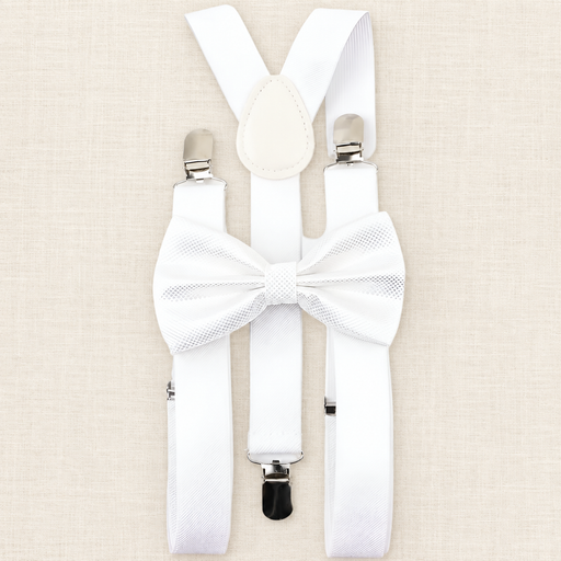 White suspenders and matching patterned bow tie arranged on ivory linen