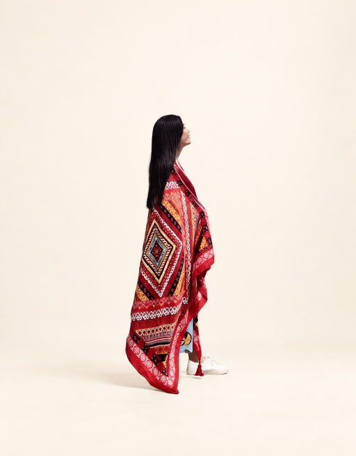 Red geometric shawl worn by model against warm ivory background