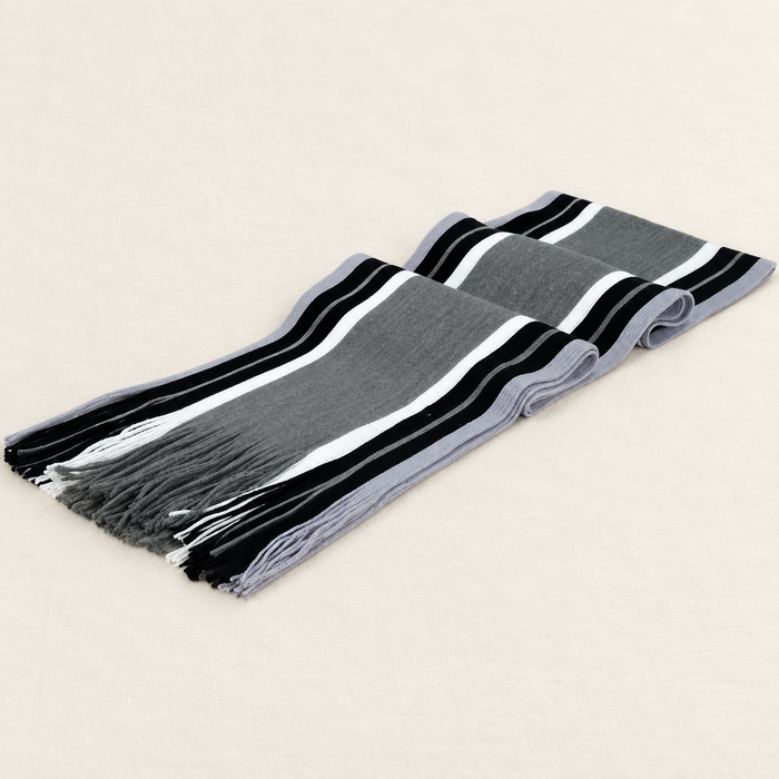 Grey striped fringed scarf folded on ivory textile