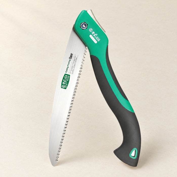 Green and black folding pruning saw shown open on a light surface