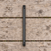 Black camping folding saw in its closed cylindrical form on a weathered wooden picnic table.