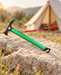 Green camping hammer with red wrist strap on pale stone beside a tent.