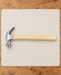 Claw hammer with a pale wooden handle on an ivory work mat.
