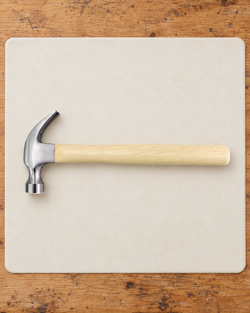 Claw hammer with a pale wooden handle on an ivory work mat.