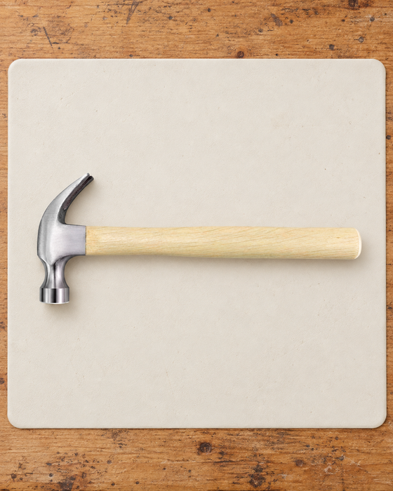Claw hammer with a pale wooden handle on an ivory work mat.