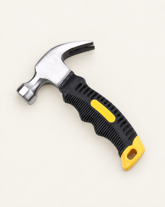 Compact silver claw hammer with a black and yellow grip on an ivory mat.